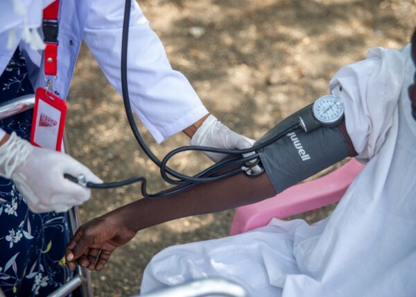 Dr. Marwa checks a patient's blood pressure outside in Sudan.
