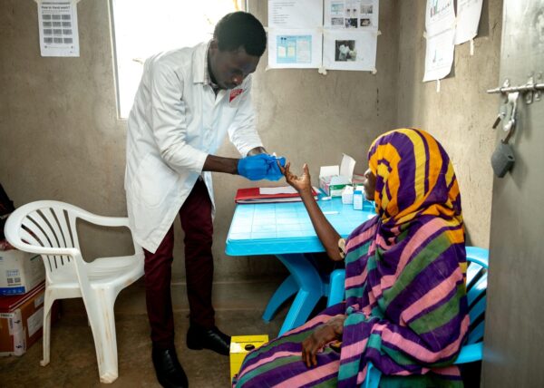 A medical lab assistant cares for a refugee in Uganda