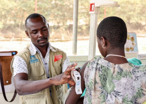 A Medical Teams health worker checks the arm circumference using MUAC tape of a woman in a clinic for refugees in Uganda to measure nutrition.