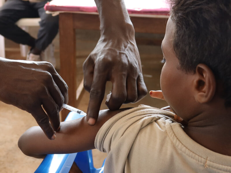 Uganda staff administers a vaccine to a Sudanese child.