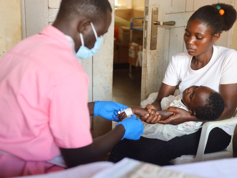 Medical Teams' Nurse passing an IV line to Keisi, Kyangwali settlement, 2023.