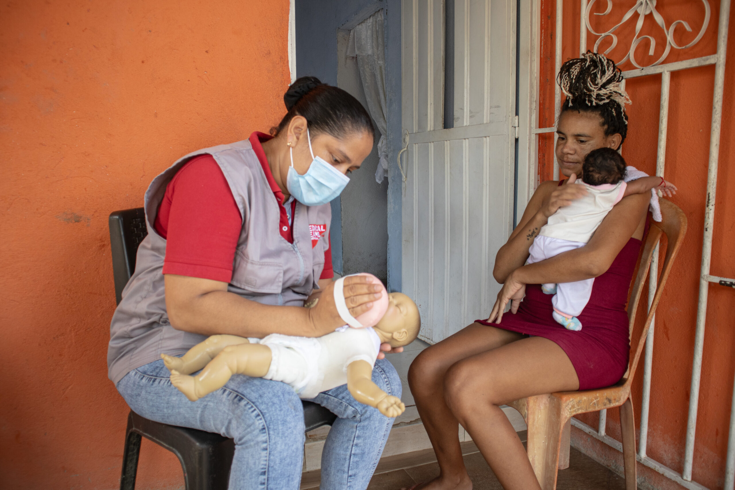 Julieth, a community health volunteer, explaining how to breastfeed to Enilsa and baby at a postnatal visit is Santa Marta, Colombia. 