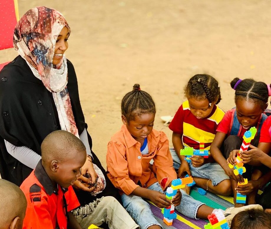 Asma sitting with kids during a play therapy session.