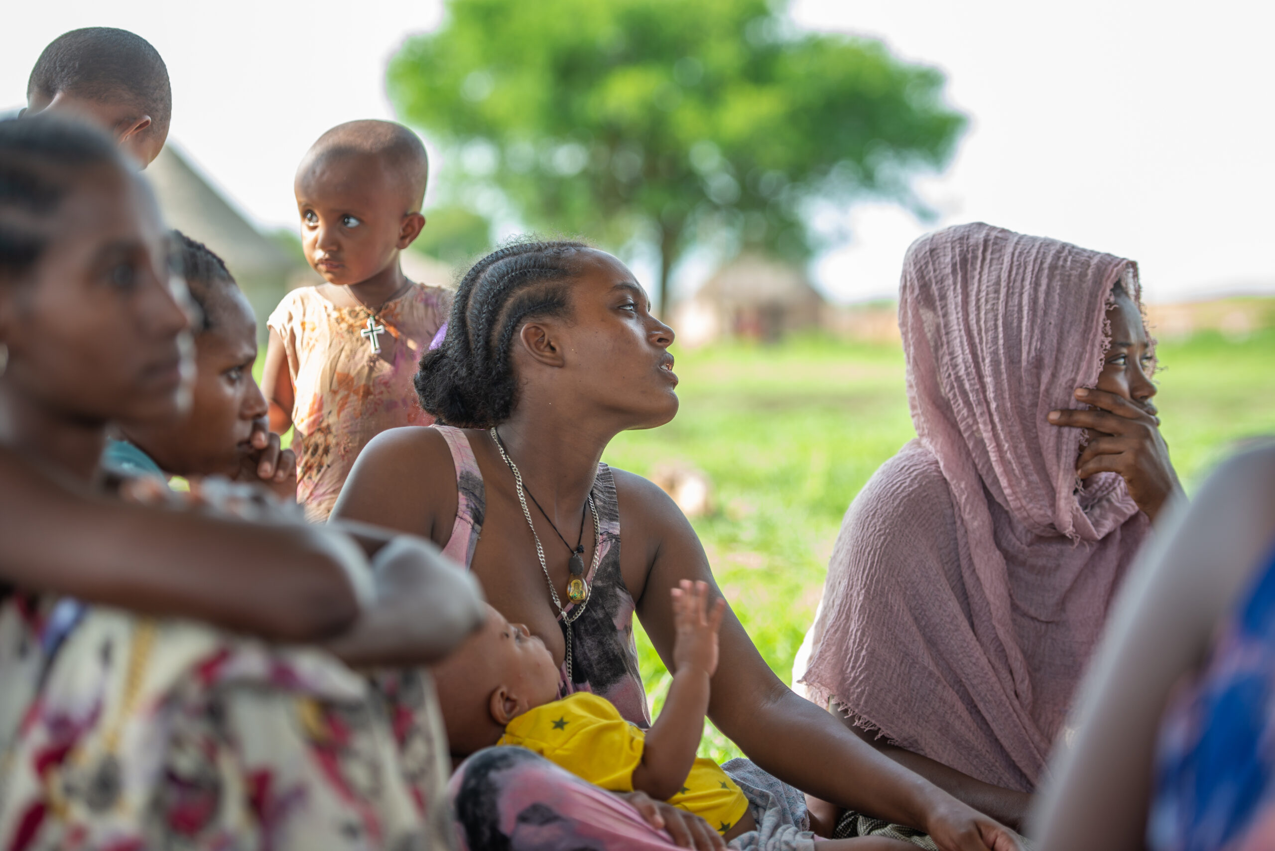 A mother feeding her baby while listening to a breastfeeding session in Sudan. 