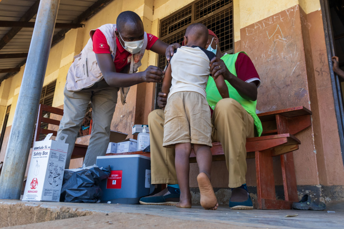 A staff member in Uganda administering a vaccine to a boy. 