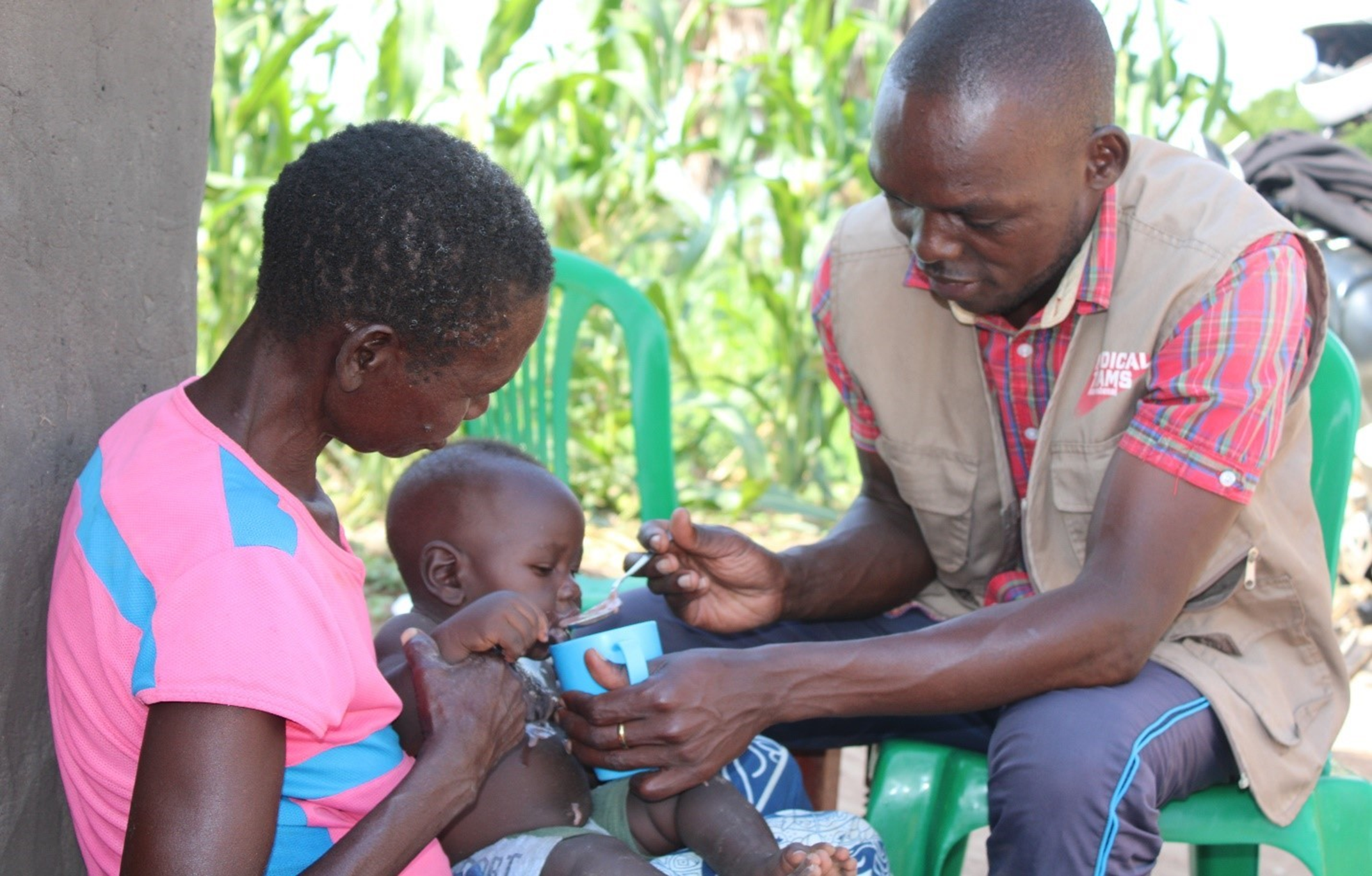 Nutritionist Innocent Omara feeding Ramsey (7 months) millet porridge enriched with groundnut paste. 