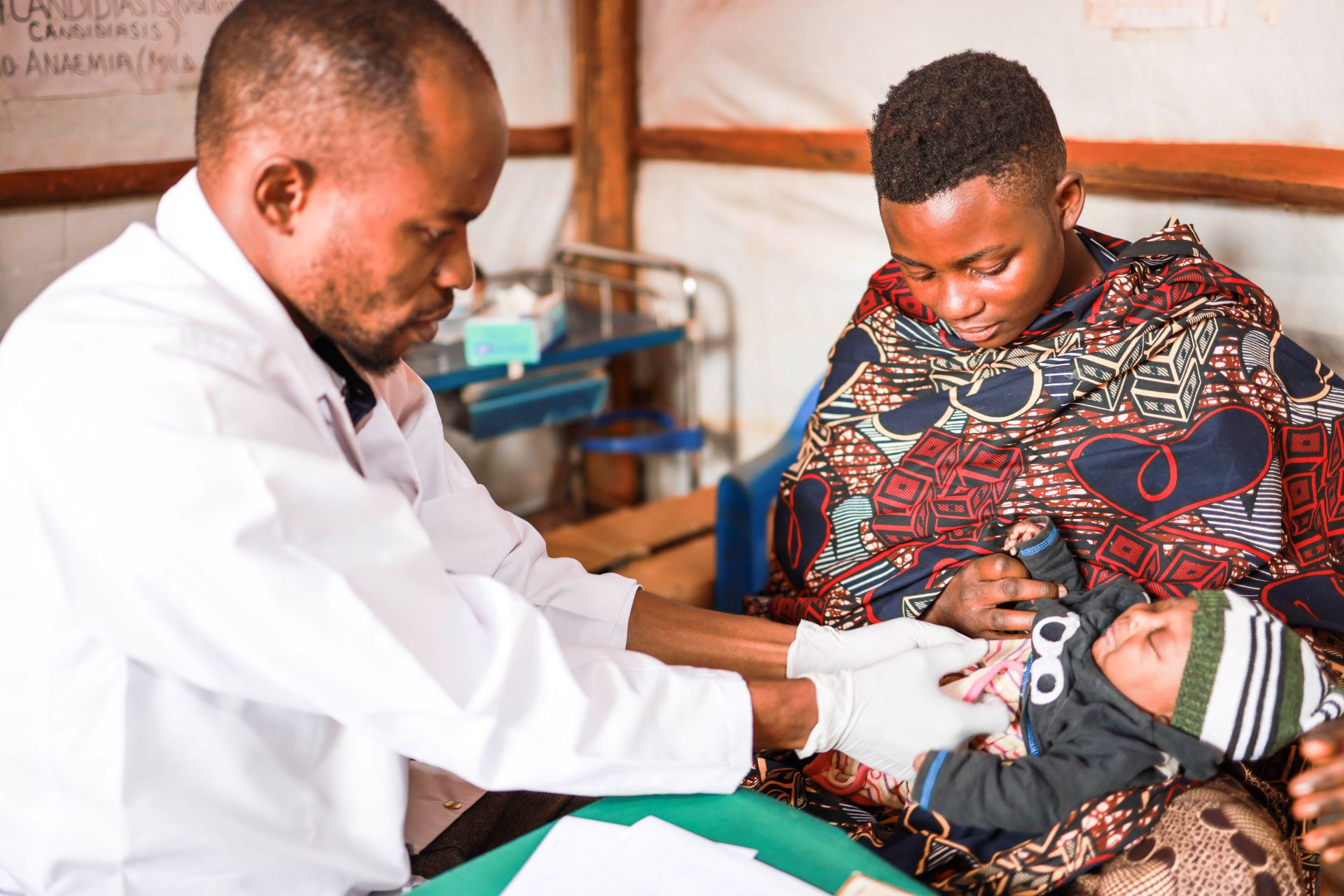 Anitha holds her baby while a Medical Teams health worker performs an exam in Tanzania