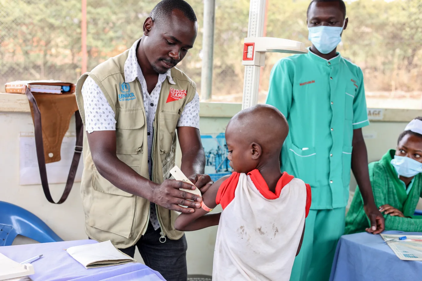 A staff member in Uganda screens a child upon etry to the Kyaka II clinic