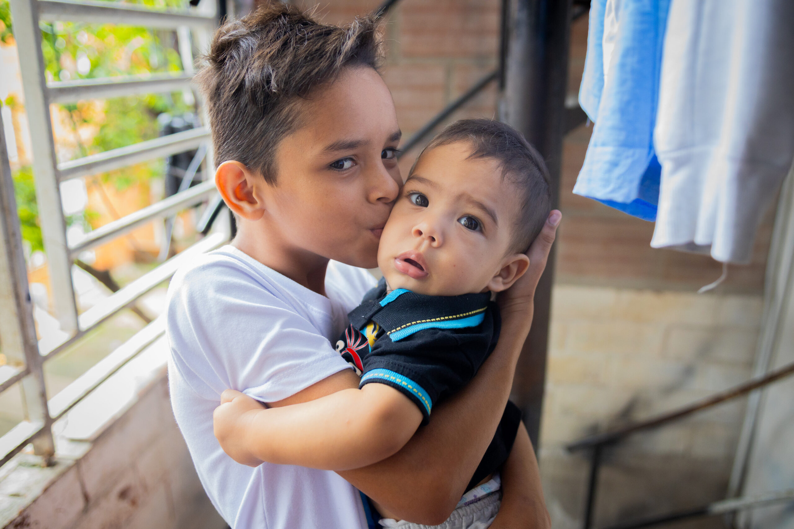 Portrait of Roiberth kissing his little brother Maikol during a home visit from a Community Health Volunteer in Cali, Colombia. 