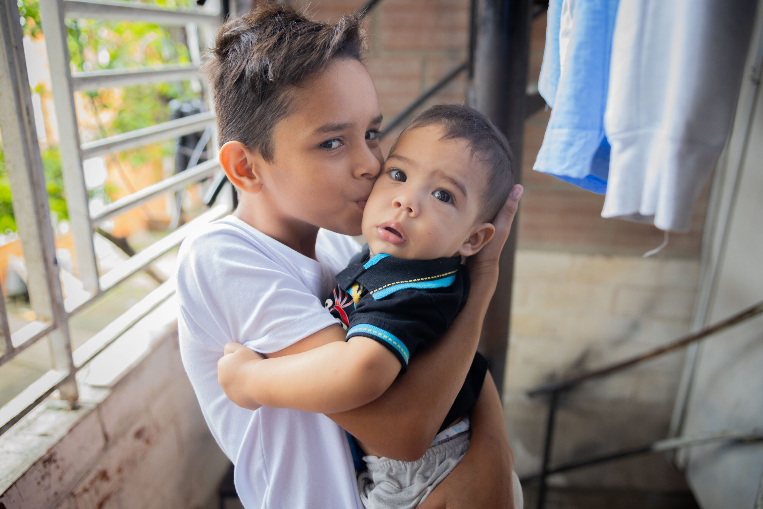 Portrait of Roiberth kissing his little brother Maikol during a home visit from a Community Health Volunteer in Cali, Colombia.