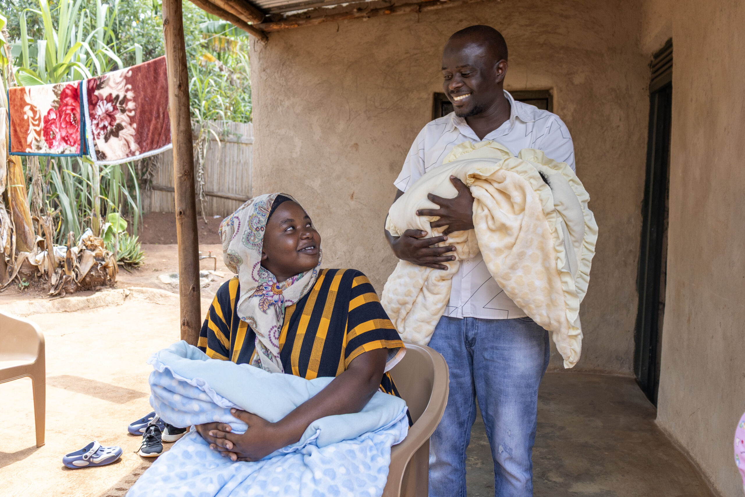 Jamil and Leila hold their twin girls and smile at each other. 