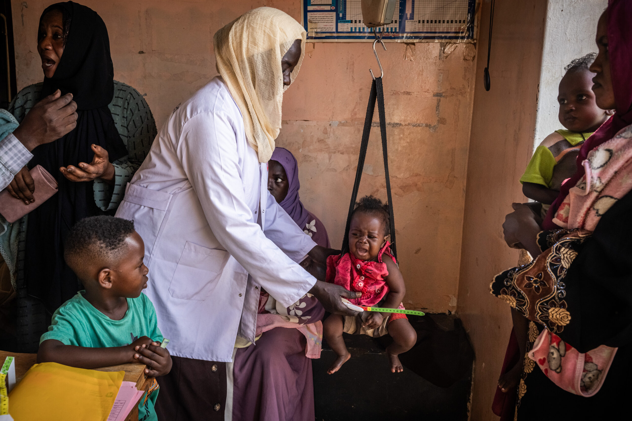 Children being screened for malnutrition and being weighed by healthcare professionals at Dar Alsalam PHC, an MTI-supported clinic in East Nile, Khartoum State. Photo by Ed Ram.