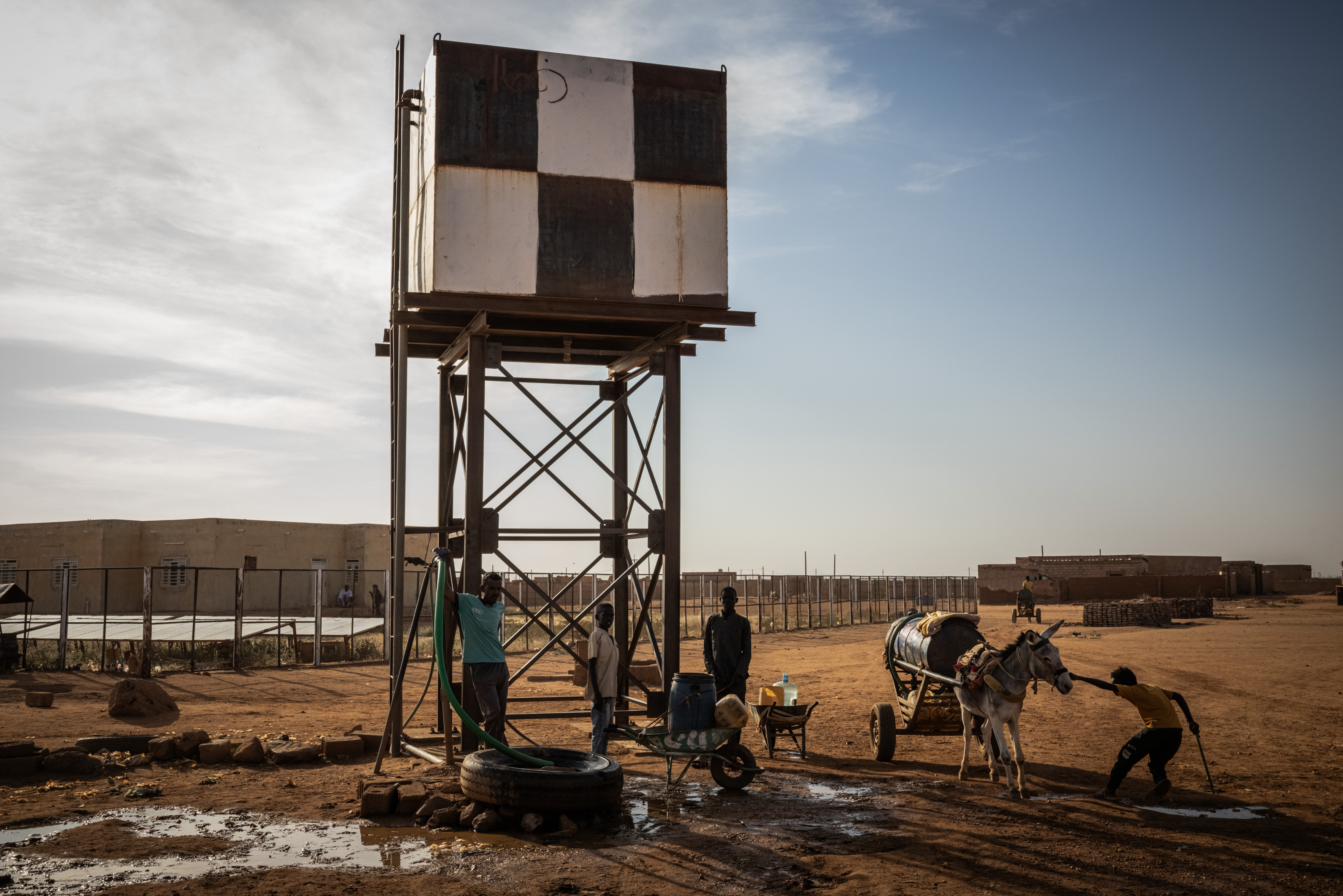 People collect water from a water point outside Bir Hamad PHC, an MTI-supported clinic in Umbada, Khartoum State, in Khartoum, Sudan. Photo by Ed Ram.