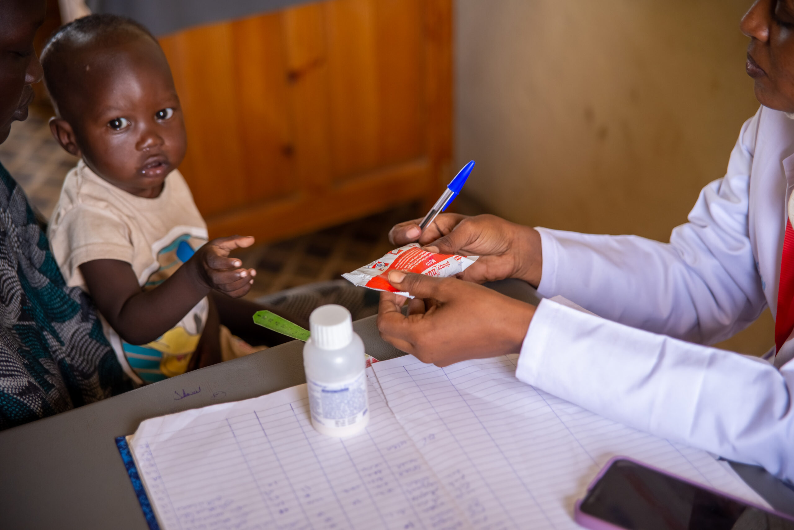A Medical Teams nutritionist hands a packet of Ready-To-Use Therapeutic Food to a child in Sudan. Fatuma received this same kind of calorie-dense food as part of her recovery.