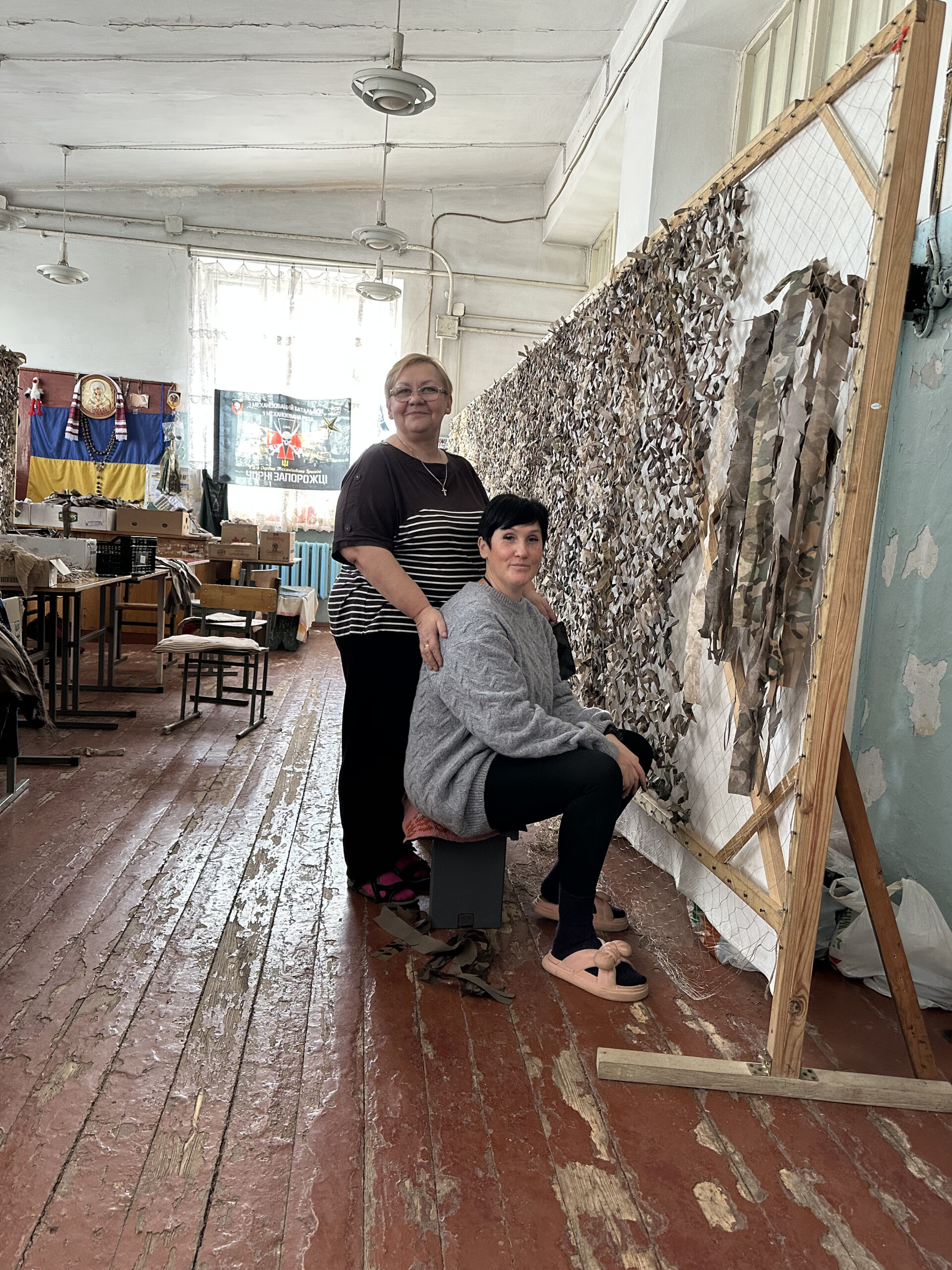 Oksana and another volunteer hand-making camouflage nets, which are used to help cover and protect infrastructure objects. 