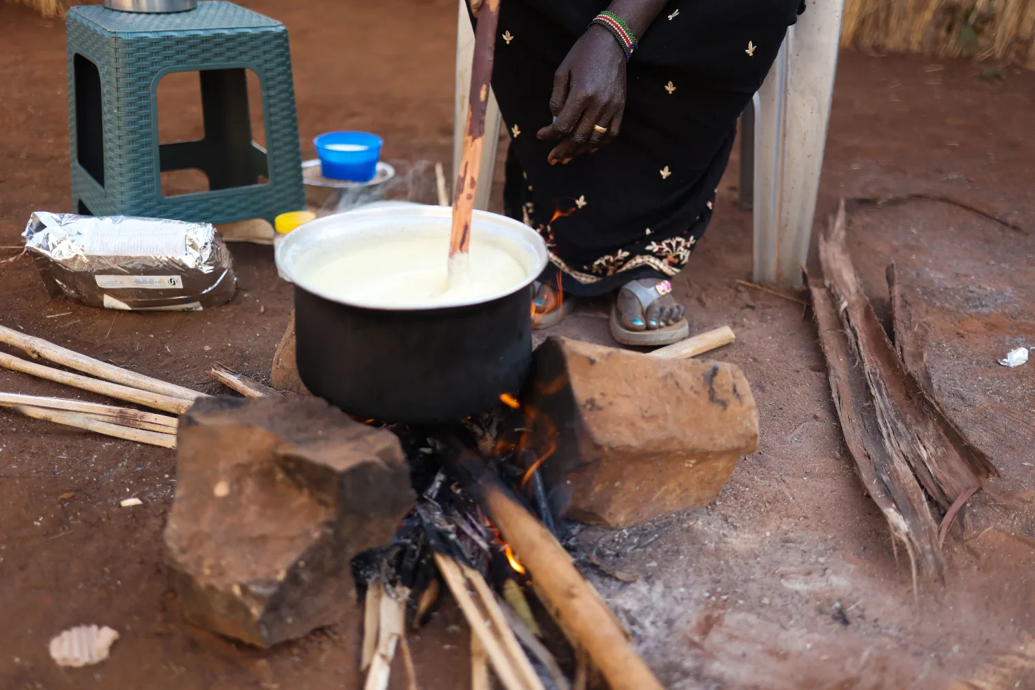 A cooking pot over a fire, with a person’s foot visible nearby.